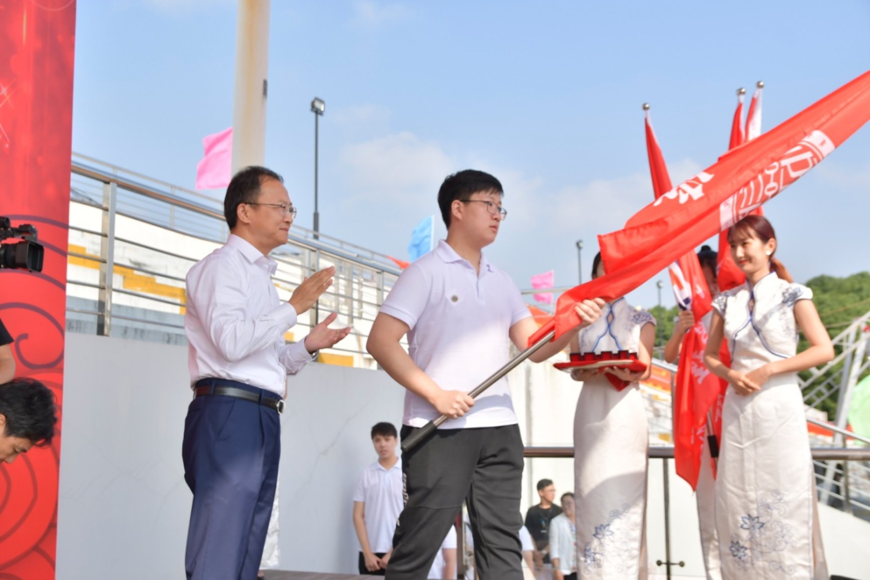 图为党委书记沈大明依次为各学院新生代表佩戴校徽、授院旗 图为党委书记沈大明依次为各学院新生代表佩戴校徽、授院旗